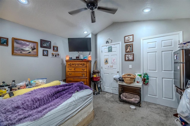 carpeted bedroom featuring lofted ceiling, ceiling fan, stainless steel refrigerator, and a textured ceiling