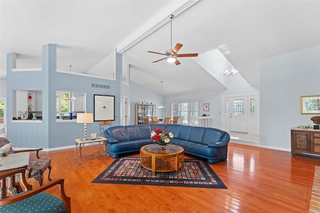 living room with hardwood / wood-style floors, ceiling fan with notable chandelier, high vaulted ceiling, and beam ceiling