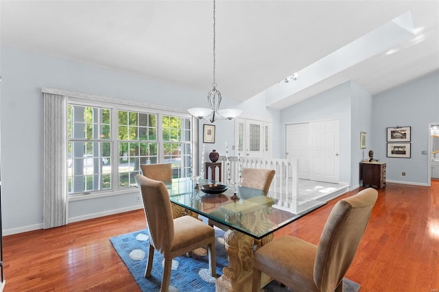 dining room with light hardwood / wood-style floors, vaulted ceiling, and a notable chandelier