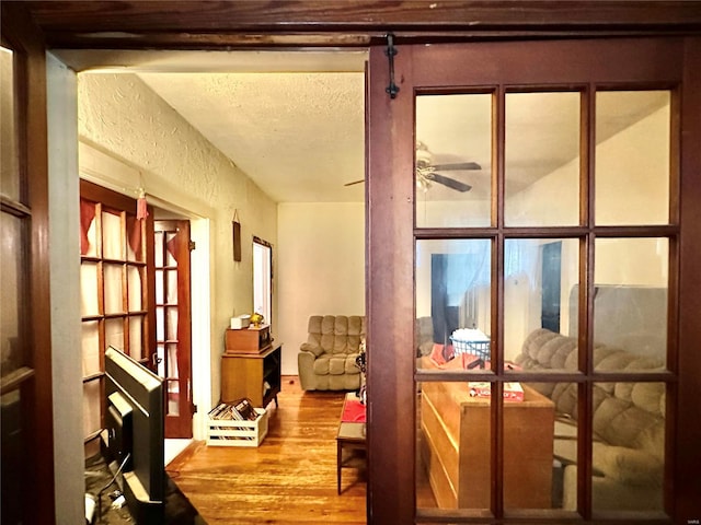 doorway to outside with ceiling fan, hardwood / wood-style flooring, and a textured ceiling