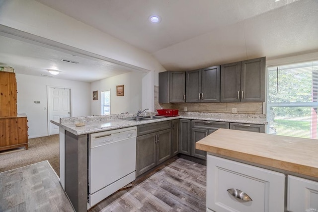 kitchen with white dishwasher, sink, kitchen peninsula, and a healthy amount of sunlight