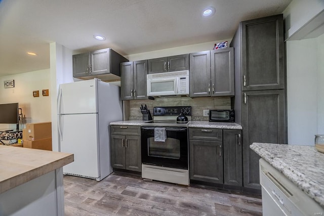 kitchen featuring white appliances, tasteful backsplash, gray cabinetry, and wood-type flooring