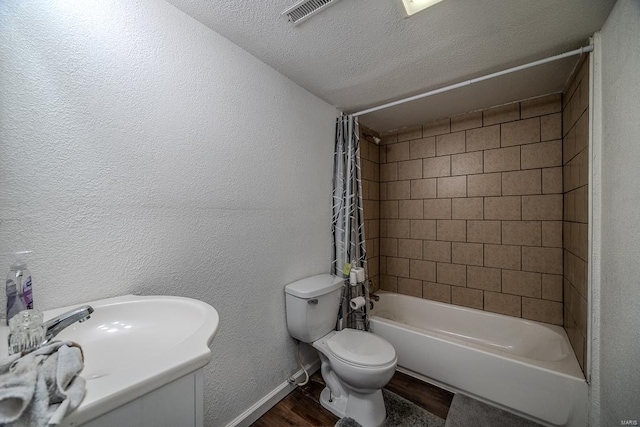 full bathroom with toilet, vanity, a textured ceiling, shower / bathtub combination with curtain, and wood-type flooring