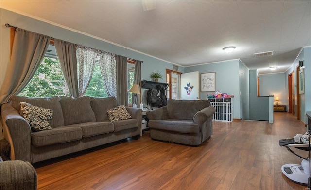 living room with wood finished floors, visible vents, and crown molding