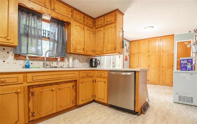 kitchen with stainless steel dishwasher, kitchen peninsula, sink, and backsplash