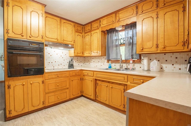 kitchen with under cabinet range hood, a sink, light countertops, black appliances, and tasteful backsplash