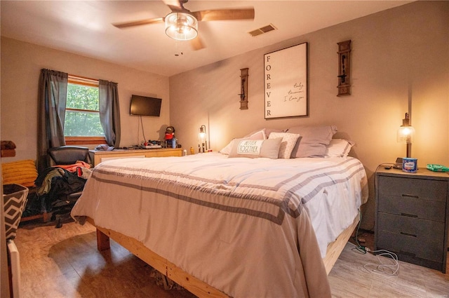 bedroom featuring ceiling fan, wood finished floors, and visible vents