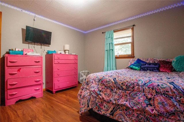 bedroom with ornamental molding and wood finished floors