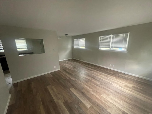 empty room with a healthy amount of sunlight, baseboards, and wood finished floors