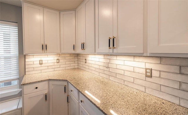 kitchen with backsplash, white cabinets, and light stone counters