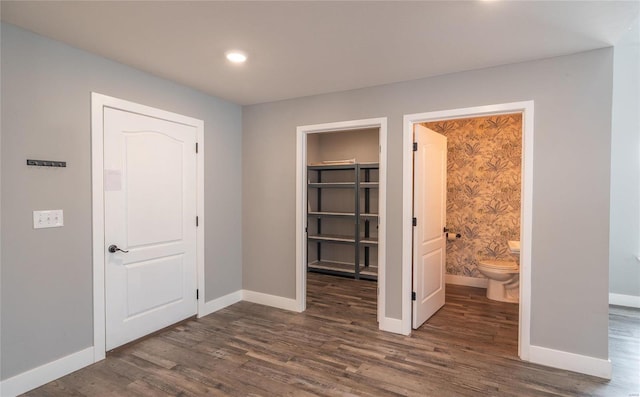 unfurnished bedroom with a walk in closet, dark hardwood / wood-style floors, ensuite bath, and a closet