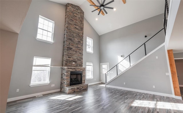 unfurnished living room with ceiling fan, a healthy amount of sunlight, a fireplace, and wood-type flooring