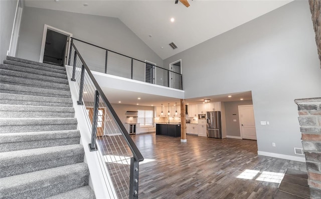 stairs featuring wood-type flooring and high vaulted ceiling