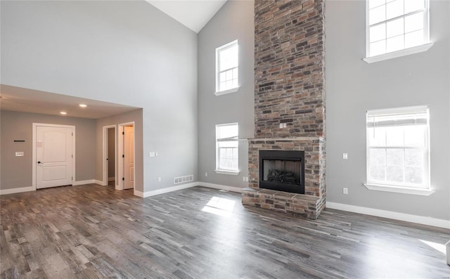 unfurnished living room featuring dark wood-type flooring, a large fireplace, and high vaulted ceiling