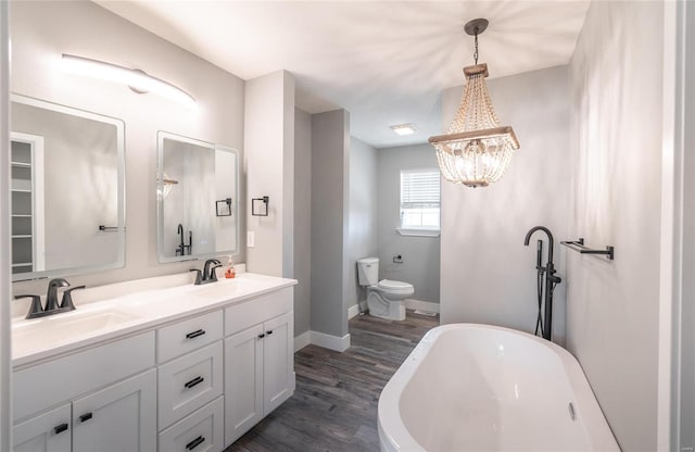 bathroom featuring hardwood / wood-style flooring, vanity, toilet, and a washtub