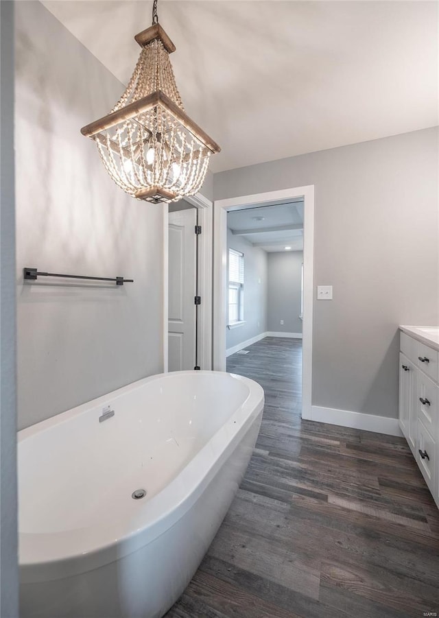 bathroom with a chandelier, vanity, a bathing tub, and hardwood / wood-style floors