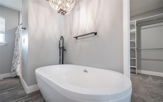 bathroom with a washtub and a notable chandelier