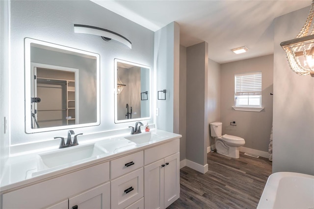 bathroom with a tub to relax in, wood-type flooring, toilet, and vanity