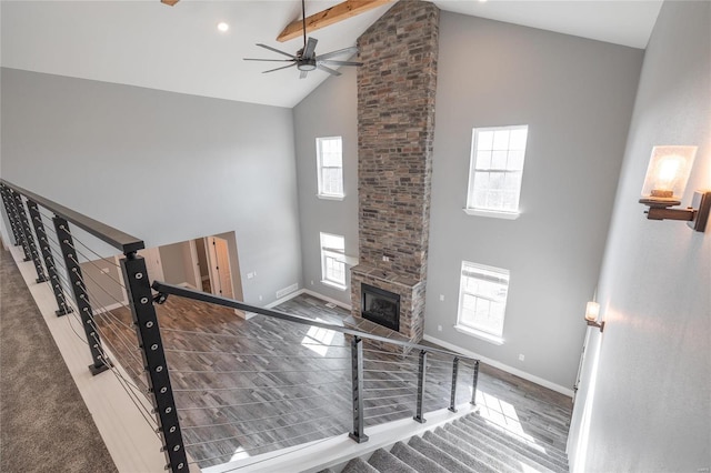 unfurnished living room featuring ceiling fan, a large fireplace, beam ceiling, and high vaulted ceiling