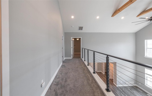 hallway with vaulted ceiling with beams and dark colored carpet