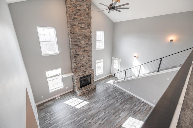 unfurnished living room with ceiling fan, dark hardwood / wood-style floors, a large fireplace, and high vaulted ceiling