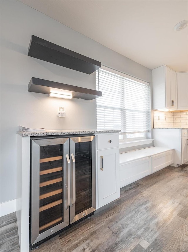 kitchen featuring white cabinetry, tasteful backsplash, beverage cooler, and light wood-type flooring