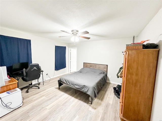 bedroom with ceiling fan, light hardwood / wood-style floors, and a textured ceiling