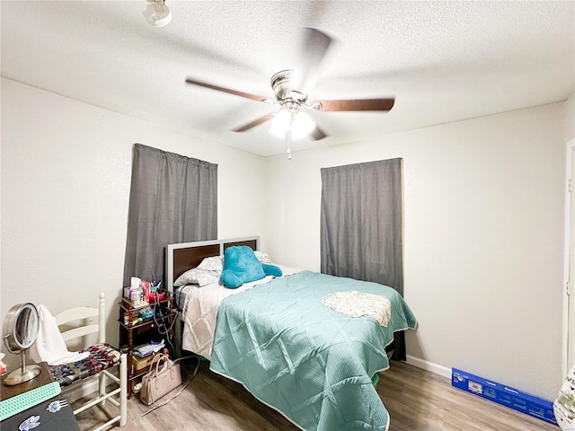 bedroom with a textured ceiling, hardwood / wood-style flooring, and ceiling fan