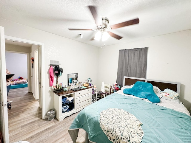 bedroom featuring ceiling fan, light hardwood / wood-style floors, and a textured ceiling