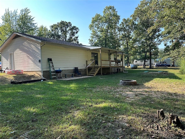 rear view of house with an outdoor fire pit and a lawn