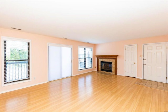 unfurnished living room with a tiled fireplace and light hardwood / wood-style flooring