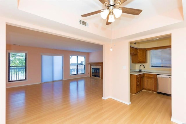 kitchen featuring sink, ceiling fan, light hardwood / wood-style floors, and stainless steel dishwasher