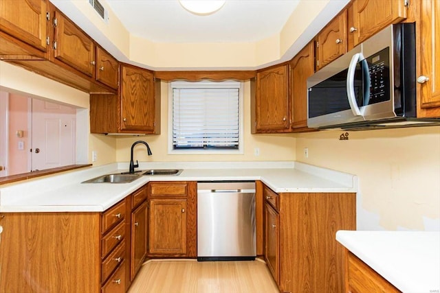 kitchen with light wood-type flooring, appliances with stainless steel finishes, and sink