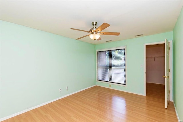 interior space featuring a closet, a walk in closet, ceiling fan, and light hardwood / wood-style floors