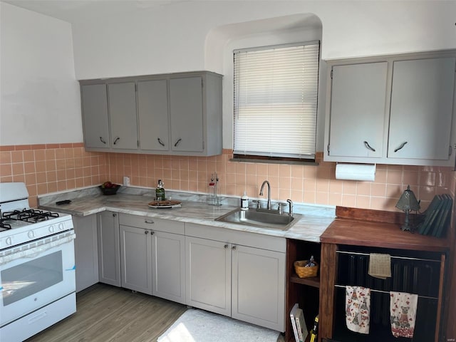 kitchen featuring decorative backsplash, sink, white range with gas cooktop, and gray cabinetry