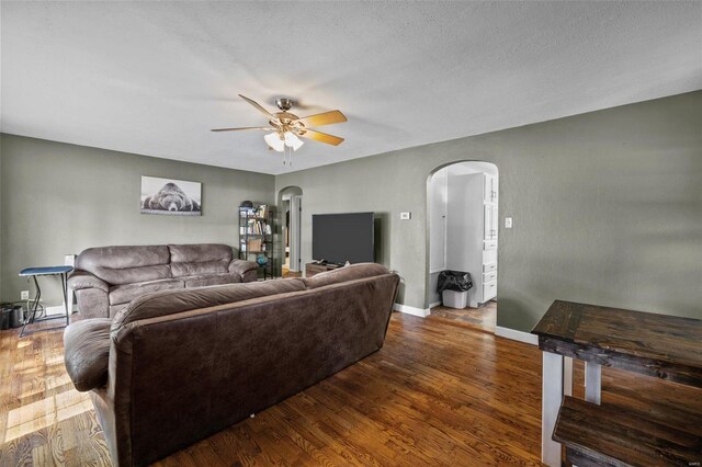 living room with ceiling fan, dark hardwood / wood-style floors, and a textured ceiling