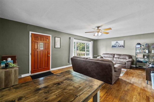 living room featuring dark wood-type flooring, a textured ceiling, and ceiling fan