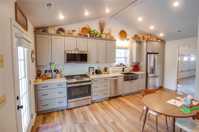 kitchen featuring gray cabinets, stainless steel appliances, sink, lofted ceiling with beams, and light hardwood / wood-style floors