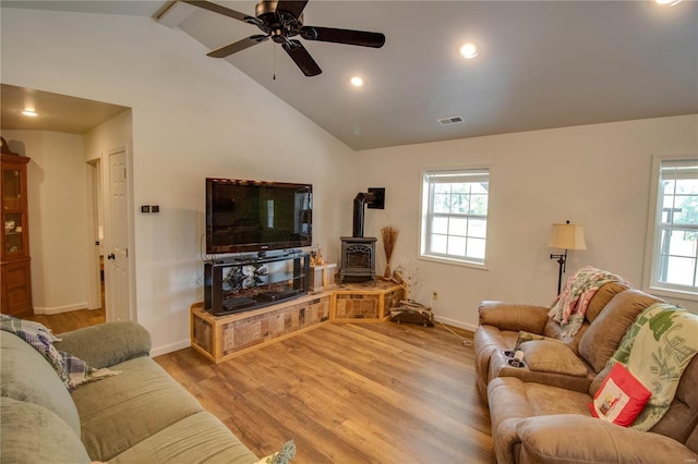 living room with a wood stove, a healthy amount of sunlight, ceiling fan, and light hardwood / wood-style flooring