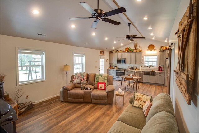 living room with beamed ceiling, wood-type flooring, ceiling fan, and a wealth of natural light