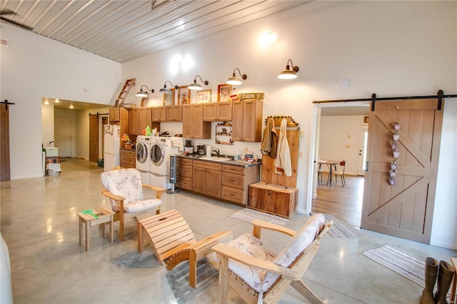 interior space with washing machine and clothes dryer, a barn door, a high ceiling, and sink