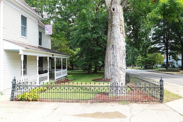 view of yard with covered porch and a fenced front yard