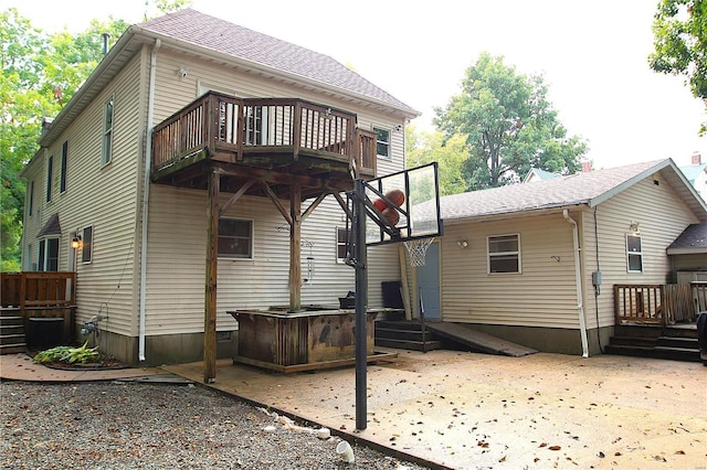 rear view of house with a deck, a patio, and a shingled roof