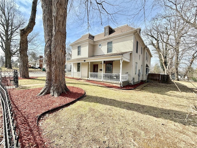 view of front facade featuring a porch, a front yard, and fence