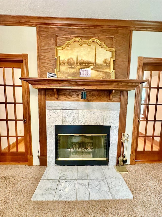 interior details with a tiled fireplace and carpet flooring