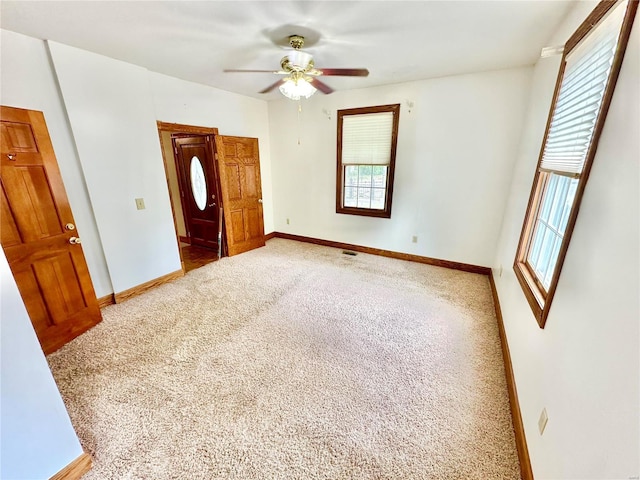 carpeted empty room with ceiling fan and baseboards