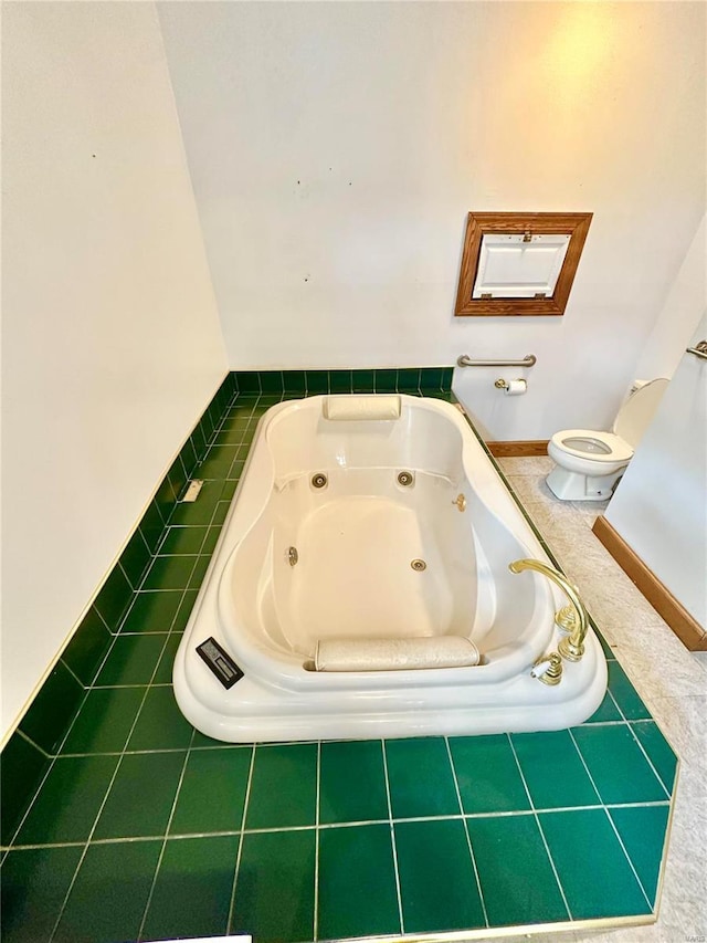 bathroom with toilet and a tub with jets