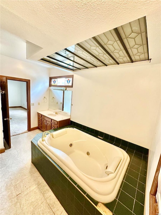 full bath featuring a jetted tub, baseboards, a textured ceiling, and vanity