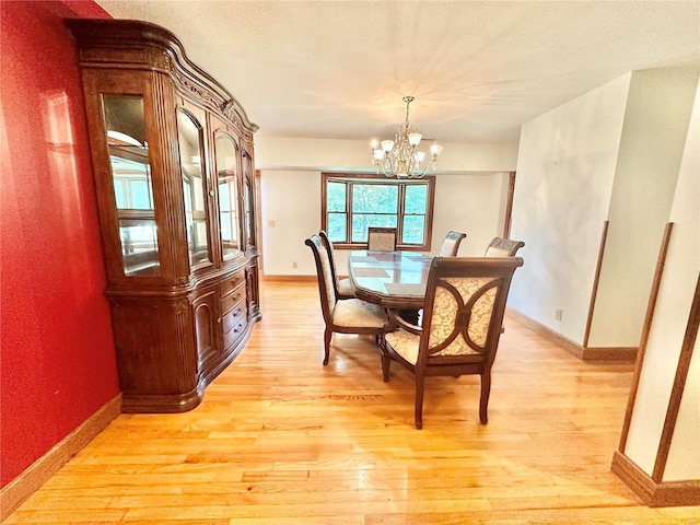 dining room featuring light wood-type flooring, baseboards, and an inviting chandelier