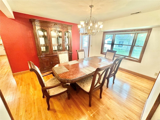 dining space with visible vents, an inviting chandelier, light wood-style flooring, and baseboards